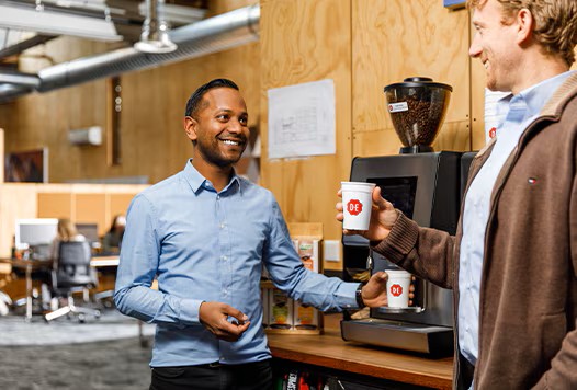 2 colleagues at a coffee machine with cups